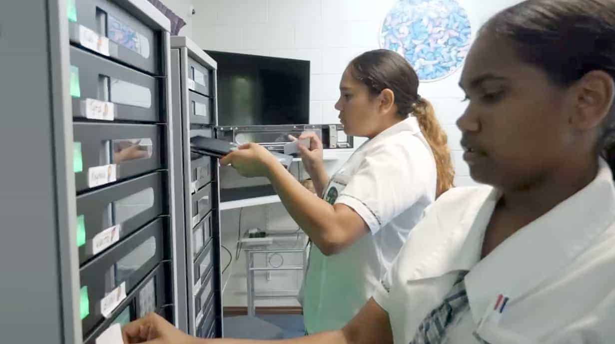Image of two students returning devices into cart