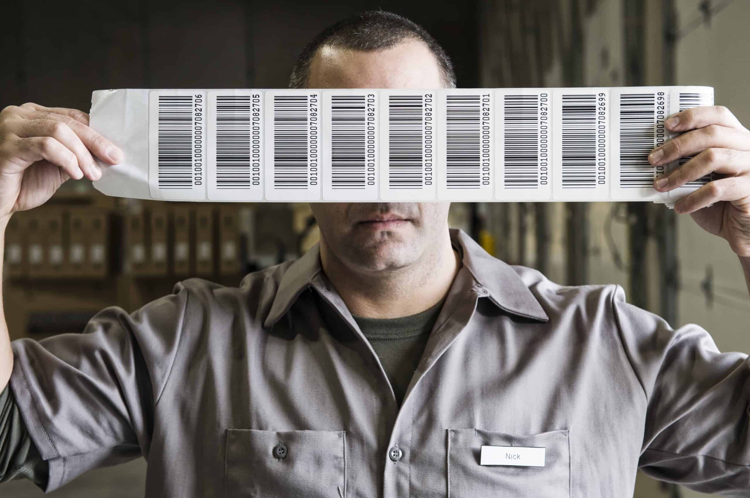 Warehouse worker holding up a sheet of bar codes